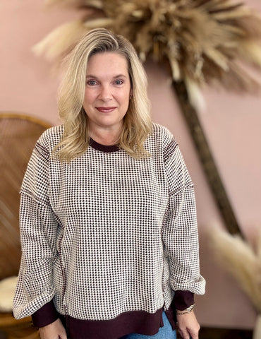 Woman wearing a checkered sweater in an indoor setting with decorative elements.