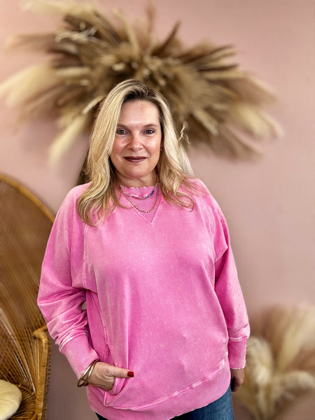 Woman wearing a pink sweatshirt standing in front of decorative elements.