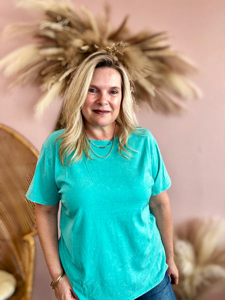 Woman wearing a teal shirt with decorative elements in the background