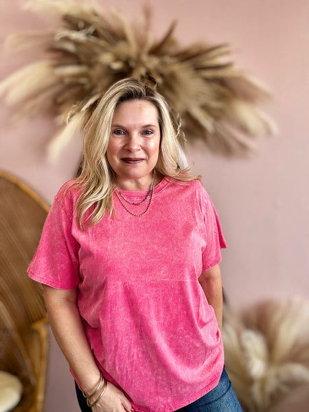 Woman wearing a pink t-shirt standing in front of decorative elements with a pink background