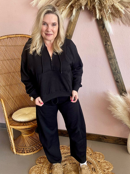 Woman in black outfit quarter zip crop sweatshirt. 