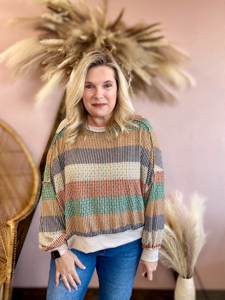 Woman wearing a colorful striped sweater.