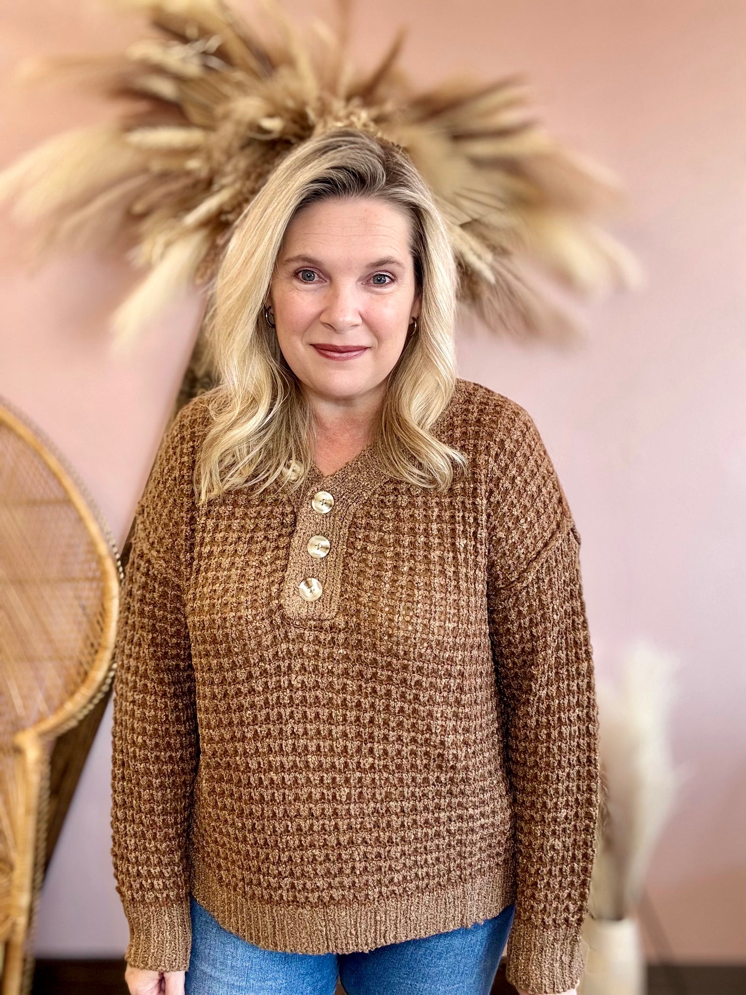 Woman wearing a brown knitted sweater with buttons in a decorative setting.