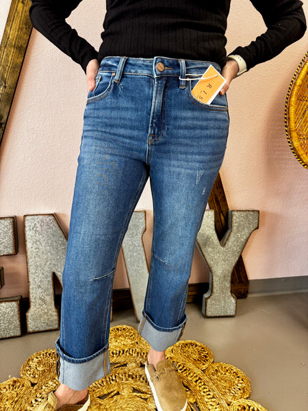 Person wearing blue jeans with a visible brand tag, standing against a decorative background.