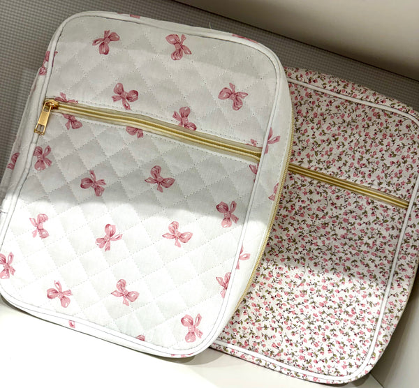 Two fabric bible covers with floral patterns and gold zippers on a neutral background