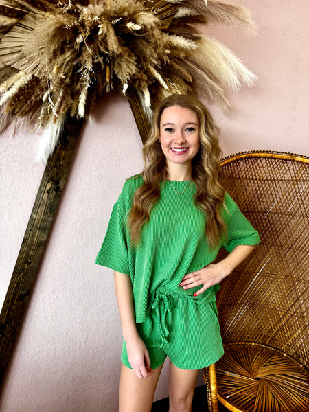 Woman in a green outfit standing next to decorative elements on a pink wall