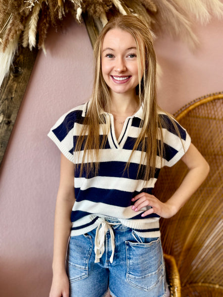 Woman wearing a striped shirt and jeans standing in front of a decorative background