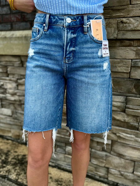 Person wearing blue denim shorts with a stone wall background