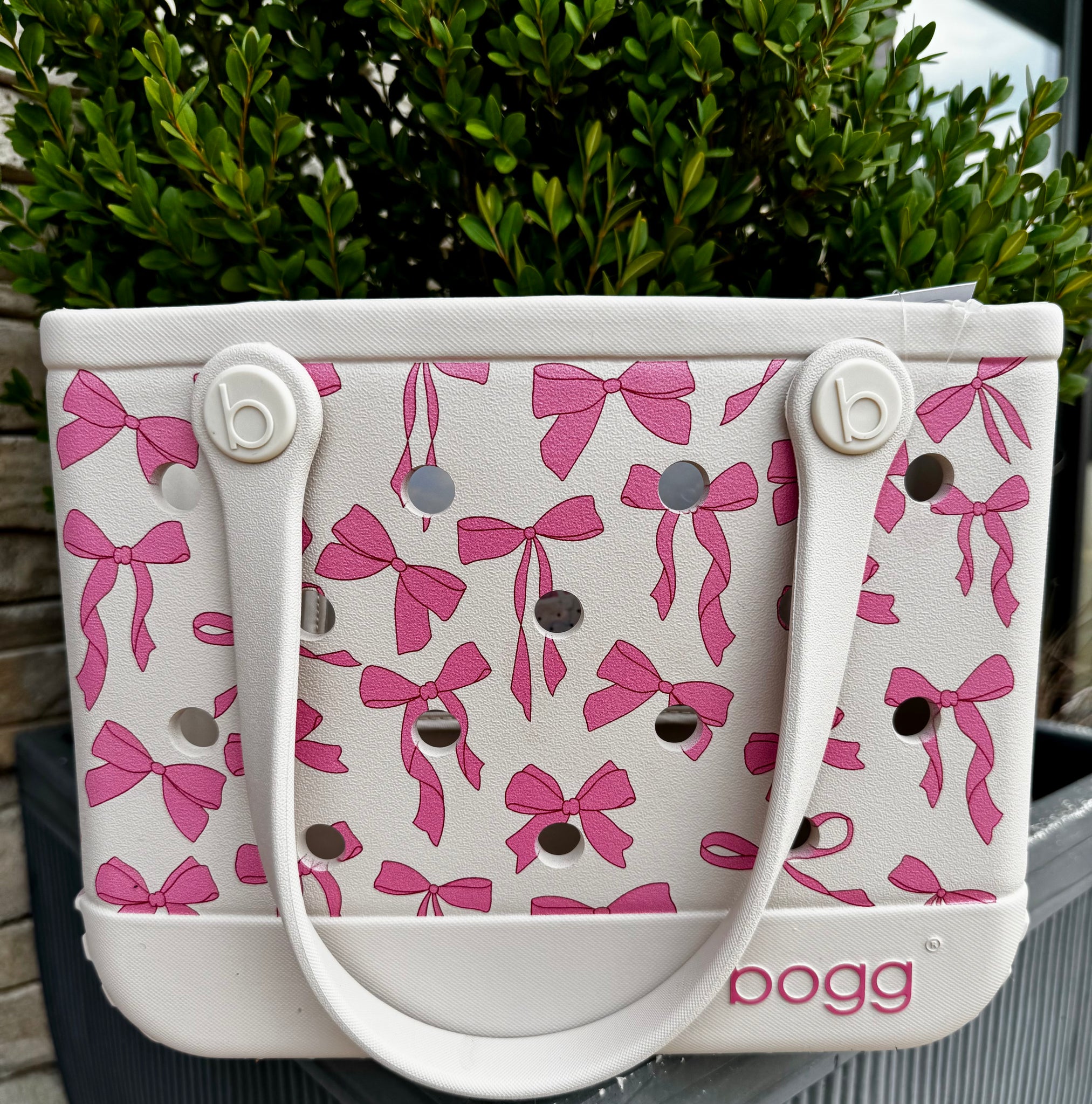 White handbag with pink bow pattern and 'bogg' branding.