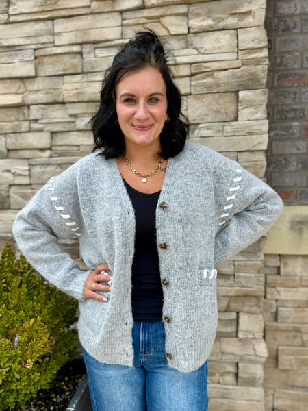 Women's light gray lightweight knit cardigan sweater with button front, long sleeves, front pockets, and white stitched details.
