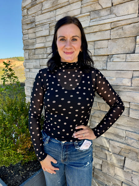 Women's black sheer mesh top with off-white polka dots, a mock neckline, and long sleeves.
