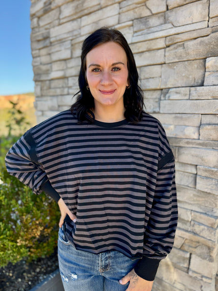 Women's charcoal and mauve striped long sleeve top featuring a wide crew neckline, relaxed drop shoulders, slightly cropped hem, and black crisscross open-back detail.