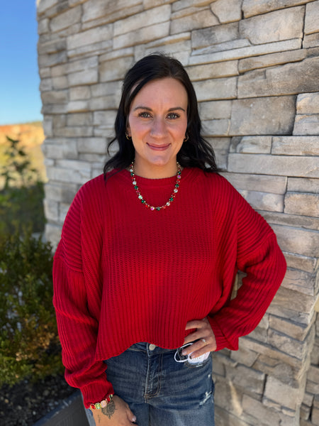 Women's red oversized ribbed knit sweater with a crew neckline, long sleeves, vertical rib texture, and subtle cropped hem.