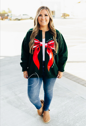 Woman wearing a green sweatshirt cardigan with a red bow design.