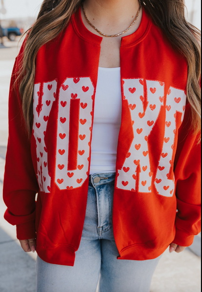 Red sweatshirt with white text and heart patterns worn by a person.
